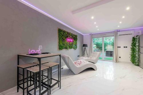 un salon avec une table et des chaises blanches dans l'établissement LOVE IN SPA Appartement Jacuzzi privé Jardin, à Escalquens