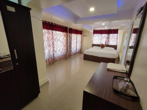 a bedroom with a bed and a window with red curtains at R R K Residency in Ooty