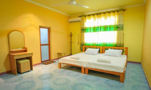 1 dormitorio con cama, espejo y ventana en Jail Break Surf Inn, en Himmafushi