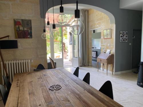 une salle à manger avec une table en bois et une cuisine dans l'établissement StSeurin Croix Blanche maison familiale en pierre, à Bordeaux