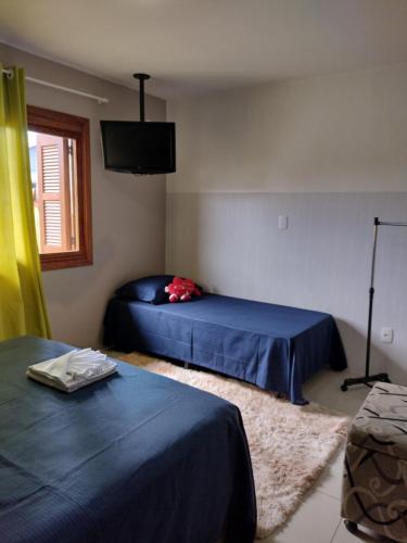a bedroom with two beds and a flat screen tv at Casa Aconchegante in Monte Belo