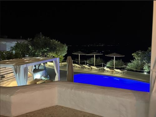 a swimming pool at night with umbrellas and chairs at Villa Mikro Chorio in Kóstos