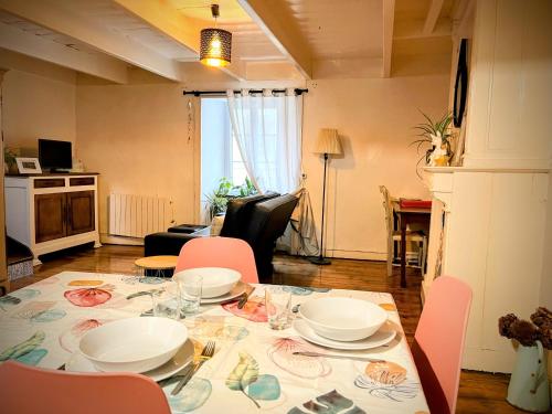 a dining table with plates and chairs in a living room at Duplex au lin in Saint-Pol-de-Léon