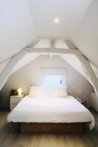 a bedroom with a white bed in an attic at Het relax hoeveke in Ostend