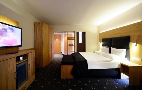 a hotel room with a bed and a flat screen tv at Ringhotel Niedersachsen in Höxter