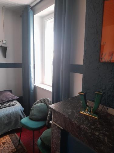 a bedroom with a bed and a table and a window at Marie-Claire la grillade in Briare
