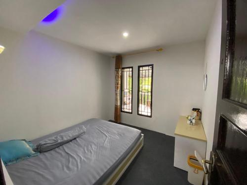 a small bedroom with a bed and two windows at Alfaz Homestay in Garung