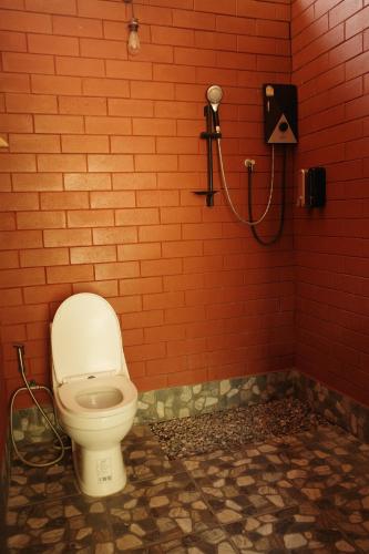 ein Badezimmer mit einer Toilette in einer roten Backsteinwand in der Unterkunft Baanraisongshul K&E Gardens in Khlong Lan