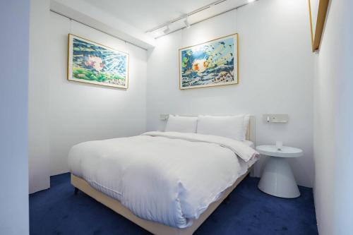 a white bedroom with a bed and a sink at 苓旅松山館 Lininn Tapei Arena in Taipei