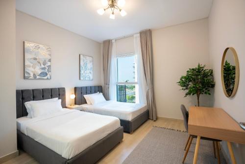 a bedroom with two beds and a desk and a window at Ferrari World & Seaworld - Luxe 2bhk Canal View in Yas Island