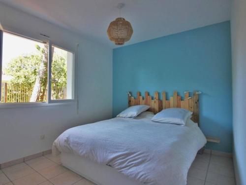 a bedroom with a bed with blue walls and a window at Villa familiale au Cap Ferret: face aux dunes, proche plage, grand jardin et terrasse, 10 pers - FR-1-736-8 in Lège-Cap-Ferret