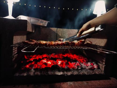 a person is cooking meat on a grill at Agriturismo il Pianetto in Principina Terra