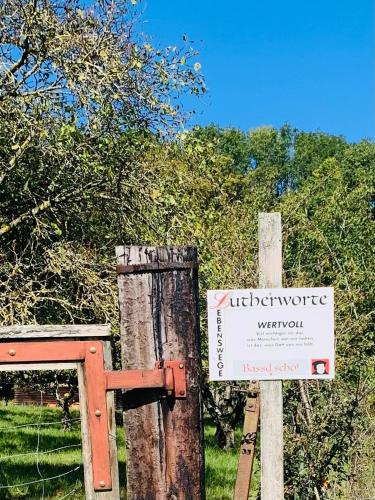 a sign on a wooden post next to a fence at Kleines Glück in Markt Nordheim