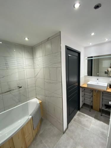 une salle de bain avec une baignoire et un lavabo dans l'établissement Lysgaardcottage 360 sauna spa bar Dancing 25V, à La Bresse