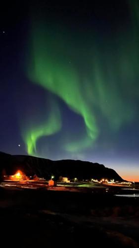 an aurora in the sky over a city at Northern Dream Lofoten in Hovdan