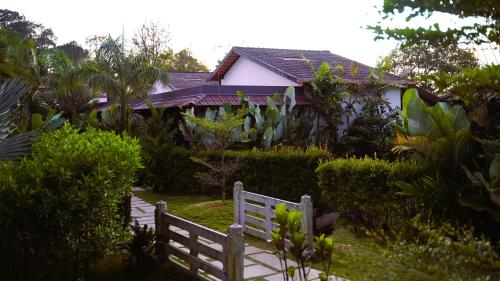 a house with a fence in a garden at Hong Sau Resort in Sakleshpur