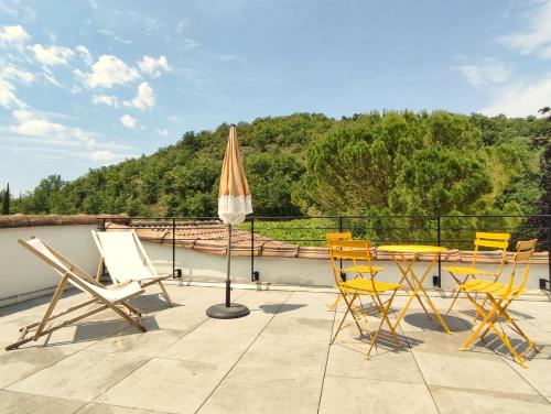 un patio avec une table, des chaises et un parasol dans l'établissement La Maison de Chagnol classée 5 étoiles, à Rochecolombe