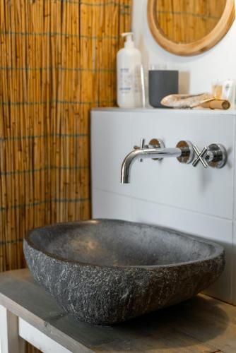 a bathroom with a stone sink and a mirror at Silver Moon Bed & Breakfast in Voorschoten