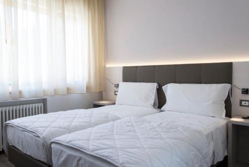 a bedroom with a large bed with white sheets and pillows at Hotel Ariston in Bolzano