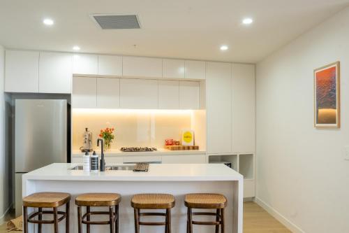a kitchen with white cabinets and bar stools at Executive Rental - Campbelltown in Campbelltown