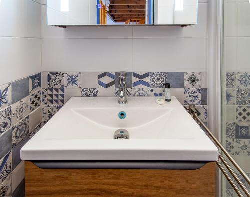 La salle de bains est pourvue d'un lavabo blanc et de carrelage bleu et blanc. dans l'établissement La Casa Di Benedetta, à Portiragnes