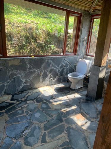 a bathroom with a toilet on a stone floor at Mộc Châu Peachy Garden in An Pon