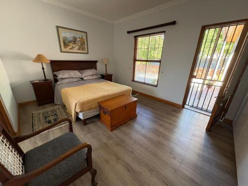 a bedroom with a bed and a couch and windows at Cozy en-suite room in Wellington with own entrance in Wellington