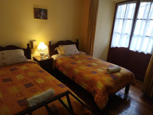 a bedroom with two beds next to a window at Hostal Montañes in La Paz
