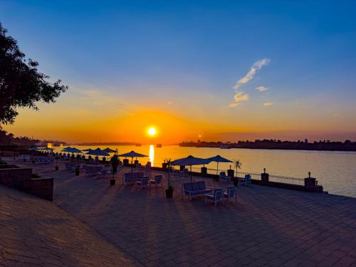 a group of chairs and umbrellas on a pier with the sunset at Stunning Nile view Apartment in Luxor