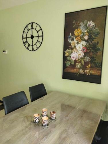 a table with chairs and a clock on the wall at Le bonheur pour tous - Gîte rural PMR en Ardennes in Tellin
