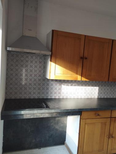 a kitchen with wooden cabinets and a black counter top at Le bonheur pour tous - Gîte rural PMR en Ardennes in Tellin