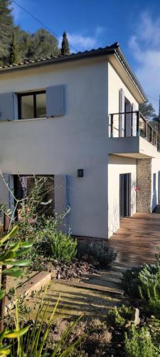 a white house with a porch and a deck at Chambres d hôtes les Romarins in Cantaron