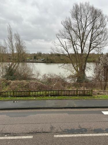 a road with a view of a river and a fence at Appartement bord de seine in Orival