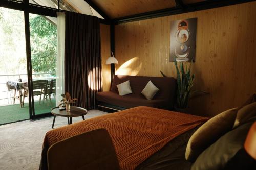 ein Schlafzimmer mit einem Bett, einer Couch und einem Tisch in der Unterkunft Baanraisongshul K&E Gardens in Khlong Lan