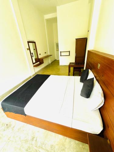 a large white bed with black pillows in a room at Tranquil Edge Villa in Haputale