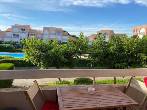 une table en bois assise au-dessus d'un banc dans l'établissement Joli studio mer balcon piscine parking privé, à Palavas-les-Flots
