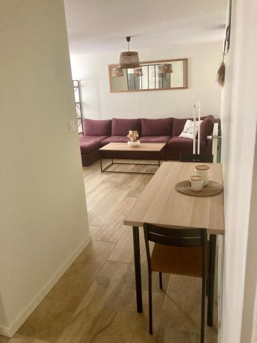 a living room with a table and a purple couch at Logement type 2 dans un parc verdoyant in Andrézieux-Bouthéon