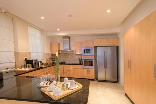 eine Küche mit Holzschränken und einem Edelstahlkühlschrank in der Unterkunft The Walden Suites in Kapstadt