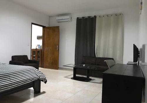 a bedroom with a bed and a couch and a table at RESIDENCE ADSL Studio MTN in Derklé