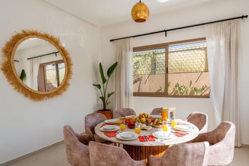 a dining room with a table and chairs and a mirror at Villa Yas, Heated Pool, 15min from City Center, 4 Bedrooms, Private Cook and Airport Pickup in Marrakech