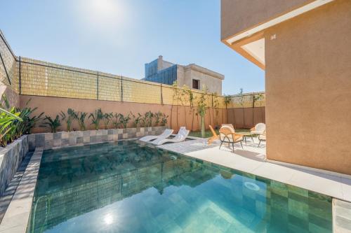 a swimming pool with two chairs next to a building at Villa Yas, Heated Pool, 15min from City Center, 4 Bedrooms, Private Cook and Airport Pickup in Marrakech