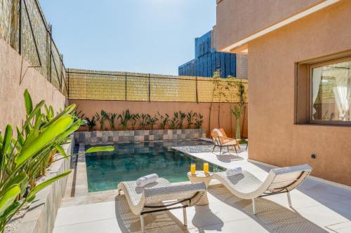 a patio with chairs and a swimming pool on a building at Villa Yas, Heated Pool, 15min from City Center, 4 Bedrooms, Private Cook and Airport Pickup in Marrakech