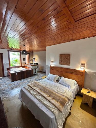 a bedroom with a large bed and a wooden ceiling at Chalés Lavras de Minas - Amar in Lavras Novas