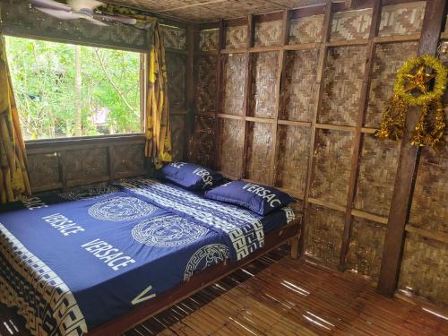 a bedroom with a bed in a room with a window at Mananambal Beach Huts - Family hut in Nagbalaye