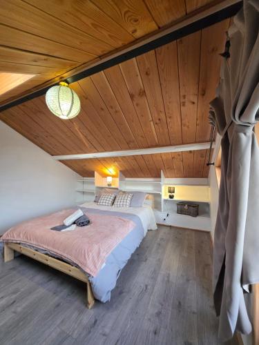 a bedroom with a large bed and a wooden ceiling at Évasion en Normandie in La Patrie