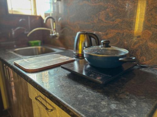 a pot sitting on top of a stove in a kitchen at Visla Stay Service Apartment near DLF Newtown in Bengaluru
