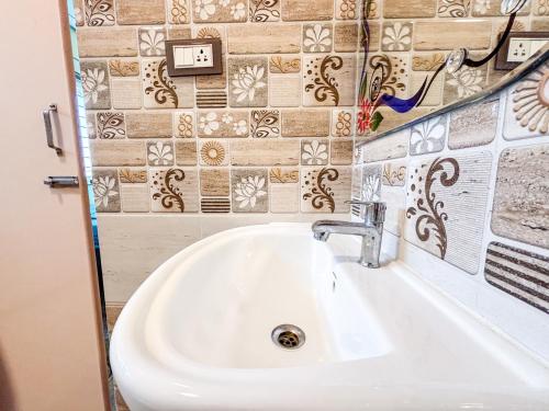 a white sink in a bathroom with tiles on the wall at Visla Stay Service Apartment near DLF Newtown in Bengaluru