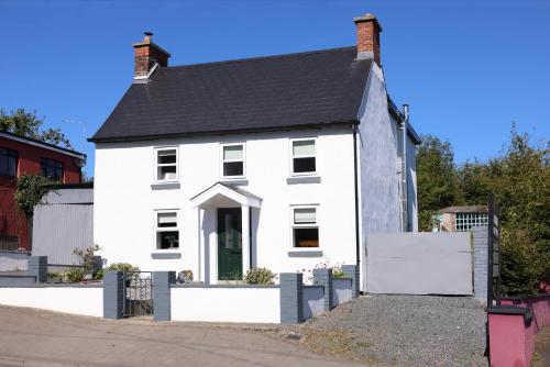 a white house with a black roof at An Teach Ban in Bunclody