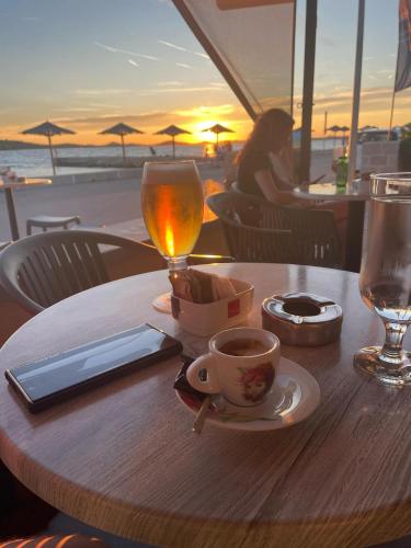 a table with a cup of coffee and a glass of wine at Apartman AS in Pirovac