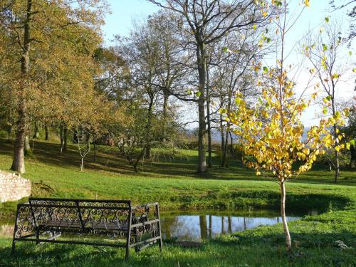 a park bench sitting in the grass next to a pond at The Larches Ledbury in Ledbury